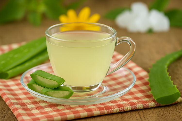 Aloe vera tea in a clear glass cup with aloe slices