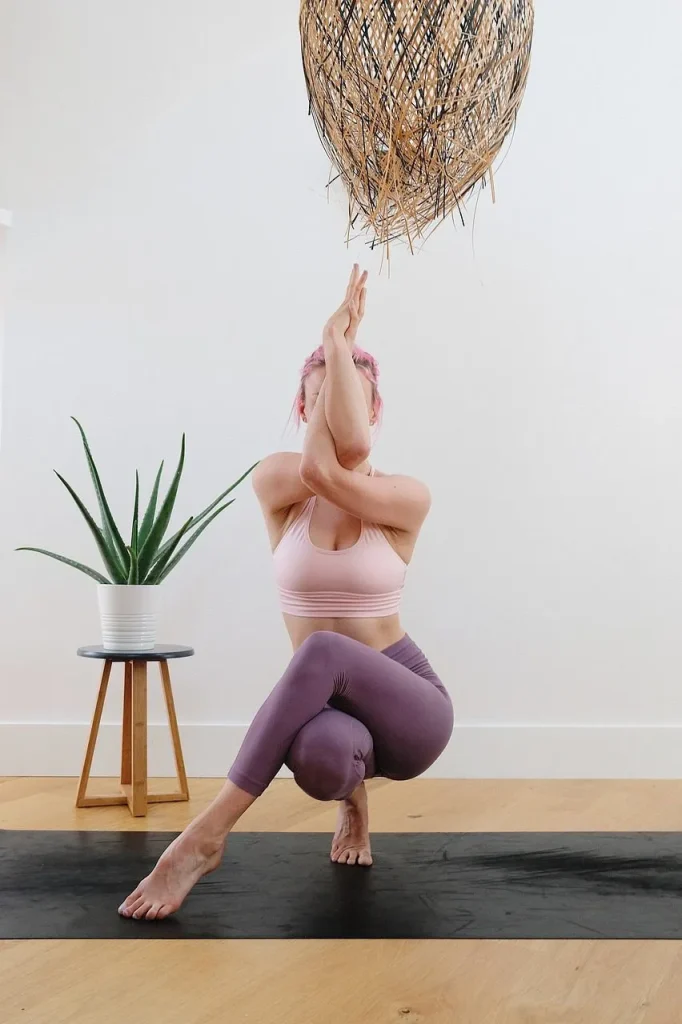 A woman practicing Garudasana (Eagle Pose) for mental focus, holistic calm, and physical balance.